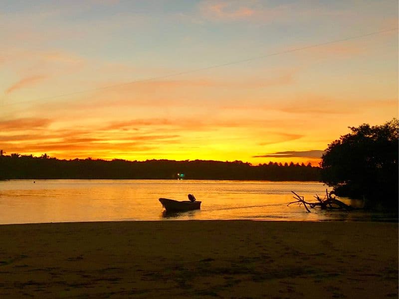 sunset over the chacahua lagoon with a fishing boat in the middle